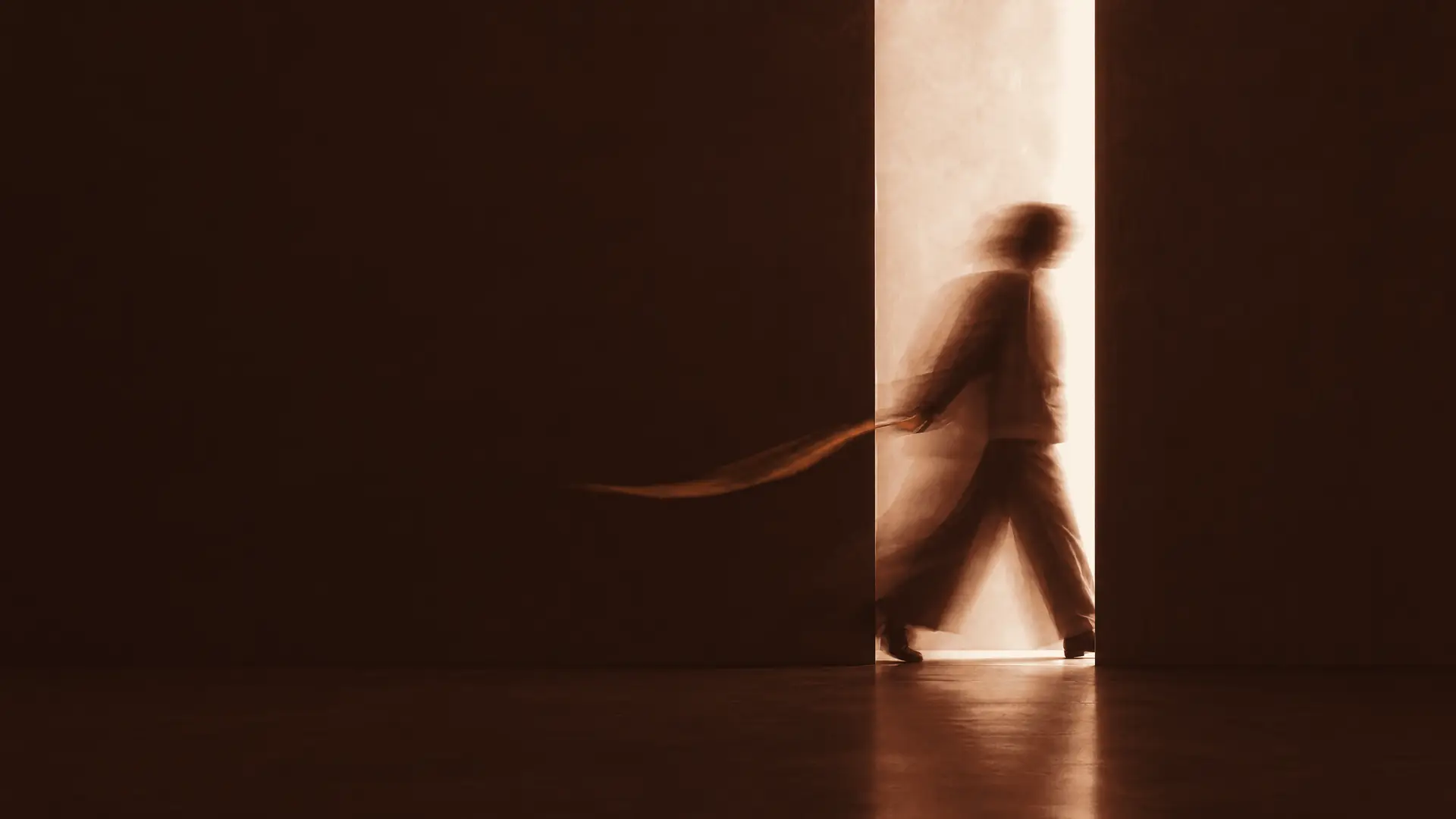A person stepping through a narrow opening of daylight, blurred by a long exposure, a ribbon of red light following their hand